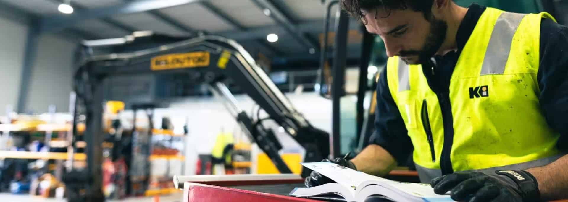 Tecnico Kiloutou che fornisce assistenza su un'attrezzatura da cantiere, evidenziando il supporto professionale e la manutenzione offerta per garantire il corretto funzionamento dei macchinari.