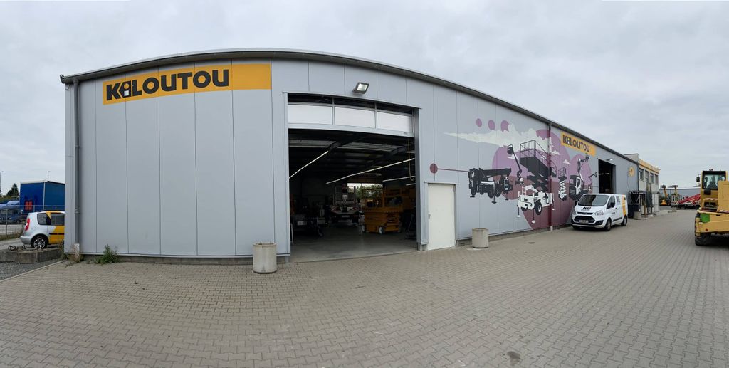 Außenansicht einer großen Kiloutou-Lagerhalle mit Maschinenillustrationen auf der Fassade, in der sich die Wartungswerkstätten befinden, um die Zuverlässigkeit der Mietgeräte zu gewährleisten.