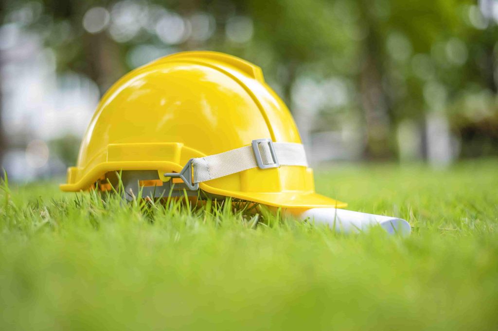 Casco de seguridad amarillo para obra colocado sobre el césped de un jardín