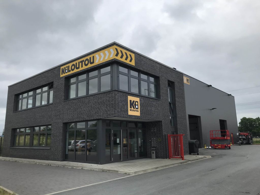 Fassade einer modernen Kiloutou-Mietstation mit dunkler Backsteinarchitektur, die Büros und eine große Lagerhalle für die Verwaltung des Mietgeräteparks vereint.